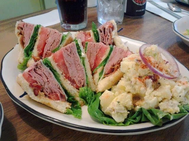 A stacked deli sandwich served with salad